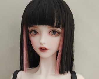 Peut inclure: Une poupée articulée au teint pâle, aux grands yeux clairs et aux lèvres rouge foncé. La poupée porte une coupe au carré noire et droite avec une frange épaisse et des mèches roses encadrant le visage, vêtue d'un vêtement rouge foncé.