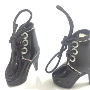 May include: A pair of black heeled boots with silver eyelets and laces. The boots have a platform sole and a pointed toe.