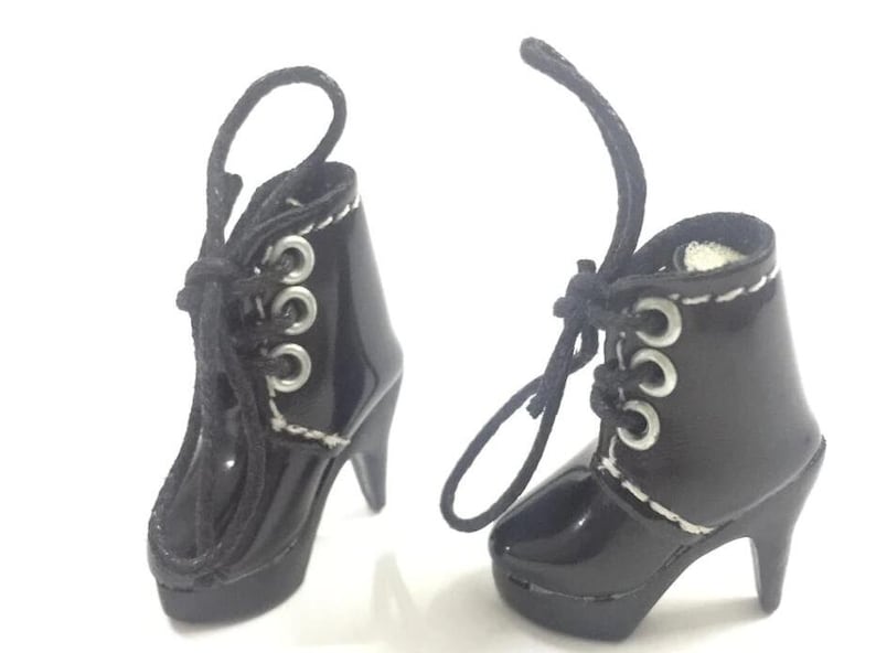 May include: A pair of black heeled boots with silver eyelets and laces. The boots have a platform sole and a pointed toe.