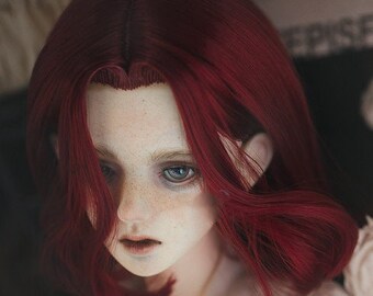 May include: A ball-jointed doll head featuring a pale complexion with visible freckles, light-colored eyes, and a neutral expression. The doll has a center-parted hairstyle with shoulder-length, deep red hair that frames the face.