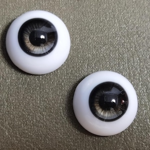 May include: Two large, round, white doll eyes with black pupils and grey irises.