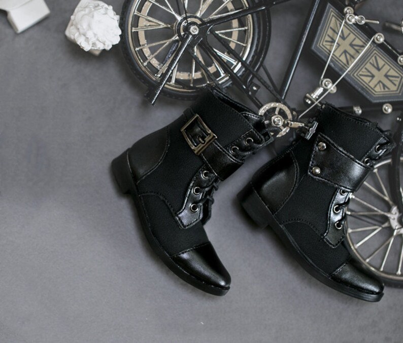 May include: A pair of black lace-up boots with buckles and pointed toes. The boots are made of a soft, textured fabric and have a sturdy sole.