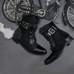 May include: A pair of black leather ankle boots with buckles and laces. The boots have a pointed toe and a low heel.