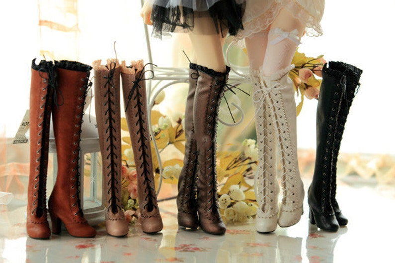 Pode incluir: Uma cole&ccedil;&atilde;o de botas altas em v&aacute;rias cores, incluindo castanho, bege e preto. As botas apresentam detalhes de atacadores e saltos altos. Algumas botas t&ecirc;m uma borda com babados na parte superior. As botas s&atilde;o exibidas em um ambiente bem iluminado.