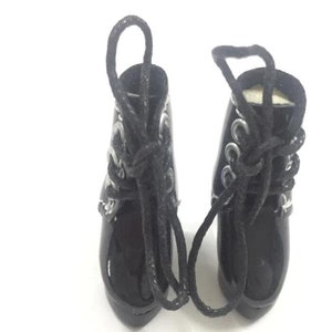 May include: A pair of black patent leather ankle boots with silver buckles and black laces. The boots have a pointed toe and a high heel.