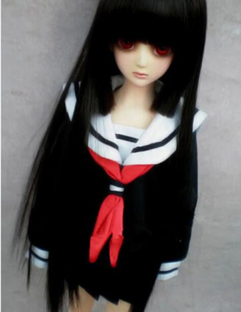 May include: A black haired doll wearing a black and white sailor uniform with a red bow tie. The doll has red eyes and a serious expression.