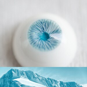 K&ouml;nnte beinhalten: Nahaufnahme eines blauen Auges mit wei&szlig;er Sklera und blauer Iris. Das Auge ist von einem wei&szlig;en Hintergrund umgeben.
