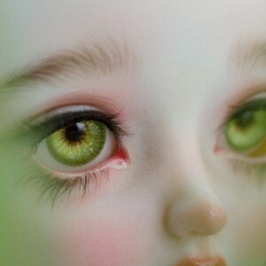 May include: Close-up of a doll's face with green eyes and long eyelashes. The doll has a light skin tone and a delicate, feminine appearance.