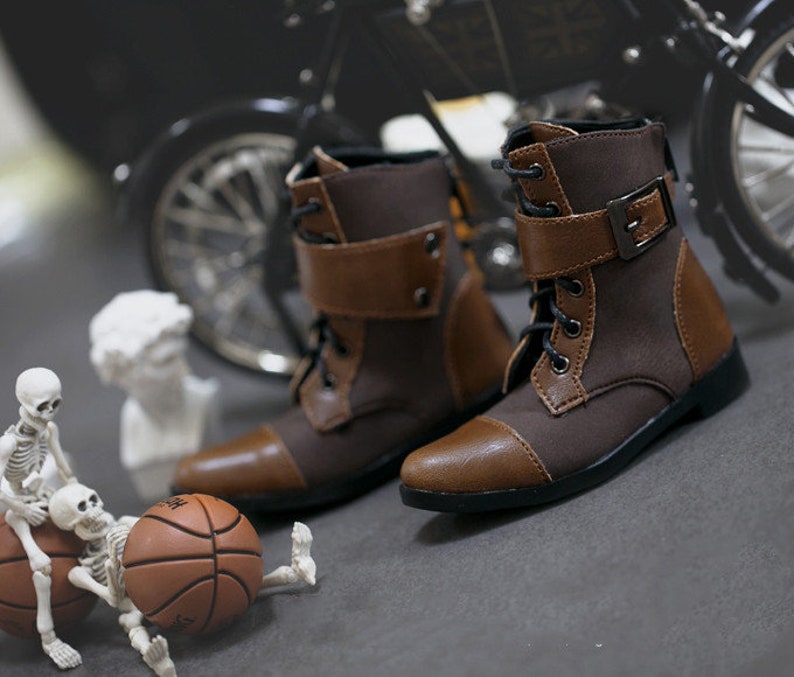 May include: A pair of brown and black leather ankle boots with buckles and laces. The boots have a rounded toe and a low heel.