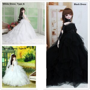May include: Three dolls wearing different dresses. One doll is wearing a white dress with a ruffled skirt. Another doll is wearing a black dress with a ruffled skirt. The third doll is wearing a white dress with a layered skirt. The dolls are all standing on a white background.