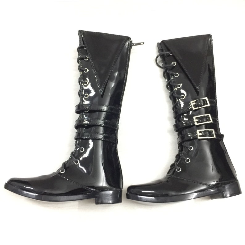 May include: A pair of black patent leather boots with lace-up fronts and buckle straps. The boots have a pointed toe and a low heel.
