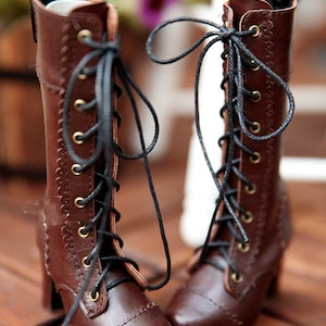May include: A pair of brown leather boots with black laces and small heels. The boots have a vintage style with decorative stitching and brass eyelets. The laces are tied in bows, and the boots are set against a blurred background.