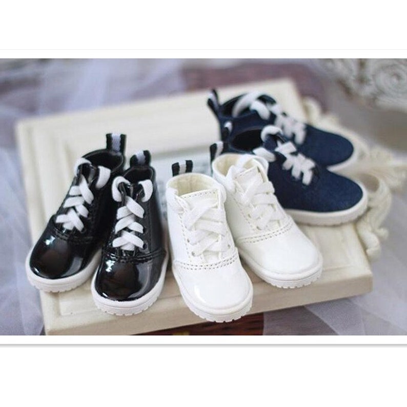 May include: Four pairs of doll shoes, two black patent leather, two white leather, and two navy blue canvas. All shoes have white laces.