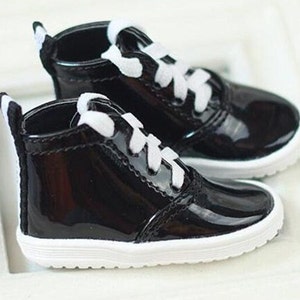 May include: A pair of black patent leather high-top sneakers with white laces and a white trim around the sole.