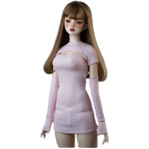 May include: A pink ribbed knit dress with a keyhole cutout at the neckline and matching long sleeves. The dress is designed for a doll.