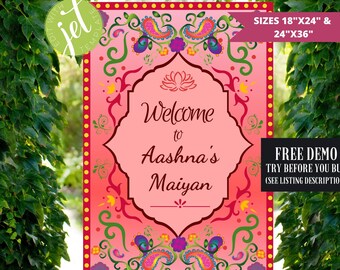 May include: A pink welcome sign with a decorative border featuring paisley patterns in shades of green, blue, yellow, and red. The sign reads "Welcome to Aashna's Maiyan" in a white font. The sign is available in sizes 18" x 24" and 24" x 36".