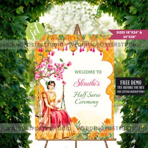 May include: A wedding sign on an easel with the text "Welcome to Shruthi's Half Saree Ceremony." The sign features an illustration of a woman in traditional Indian attire, pink flowers, and orange accents. Sizes are 45.7cm x 61cm & 61cm x 91.4cm.