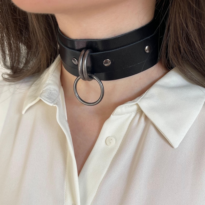 Close-up of a wide black leather collar with dark nickel hardware.
Black view.
