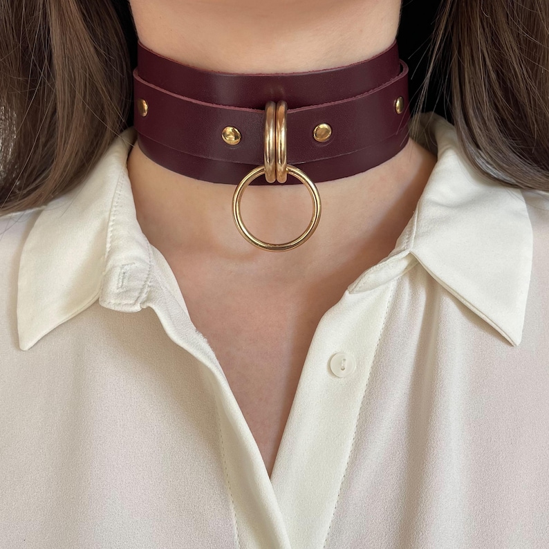 Close-up of a wide marsala leather collar with gold hardware.
Front view.