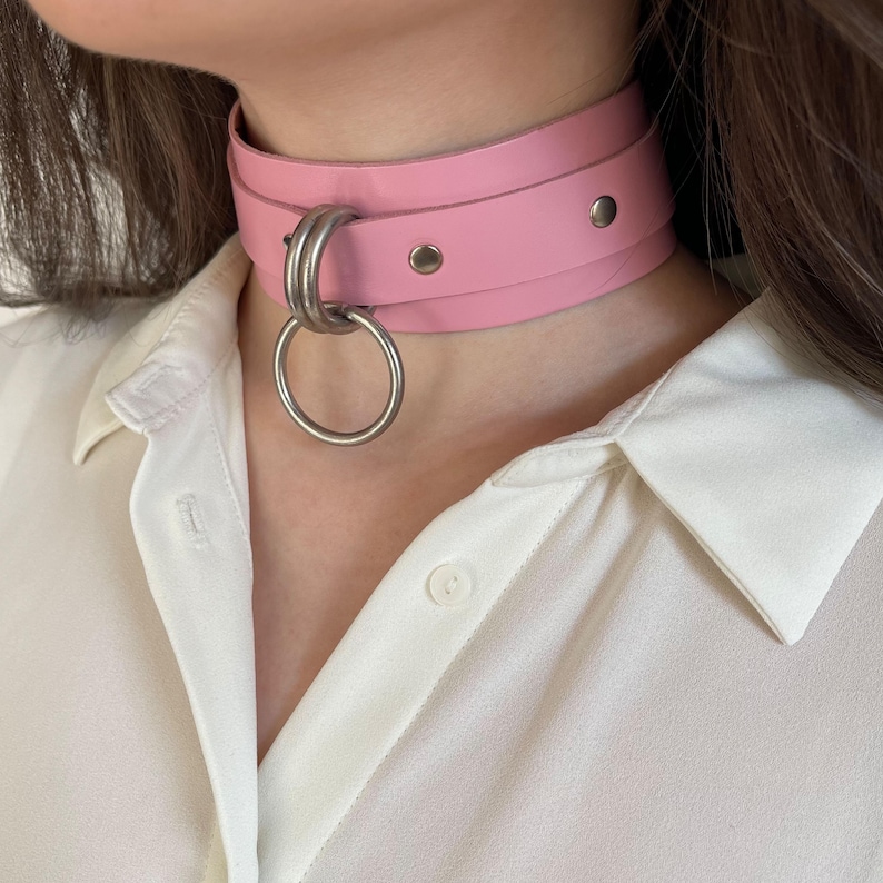 Close-up of a wide pink leather collar with silver hardware.
Side view.
