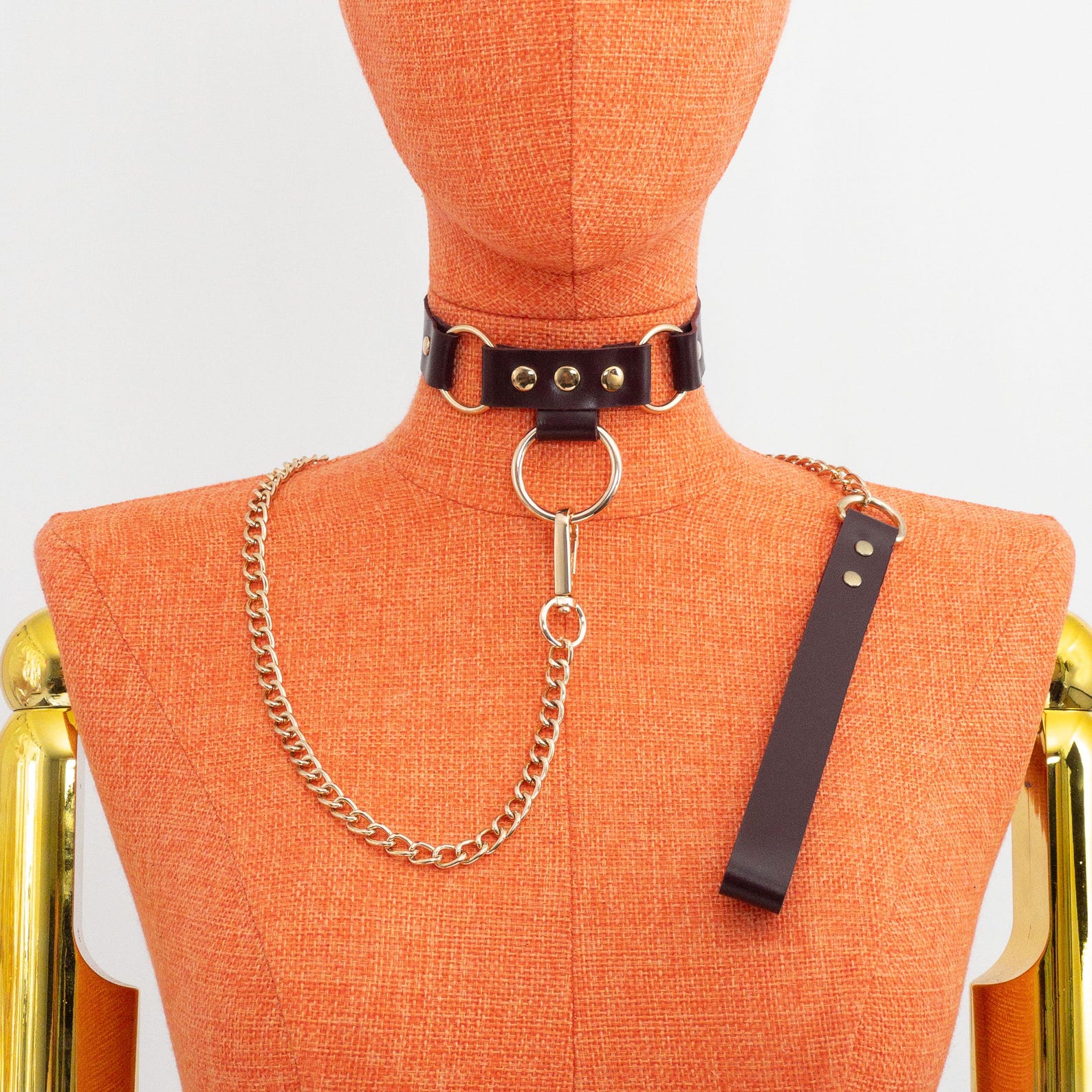 Dark brown leather bdsm collar with gold chain leash displayed on mannequin, handmade for bondage or day wear.