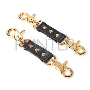 May include: Two black leather straps with gold metal clasps and studs. Each strap has four gold studs.