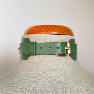 Close-up of a wide green leather collar with gold hardware.
Back view.
