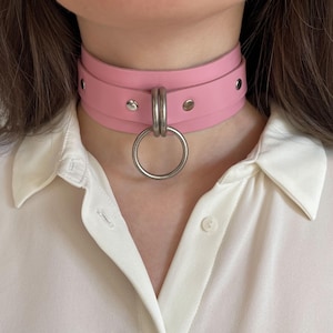 Close-up of a wide pink leather collar with silver hardware.
Front view.