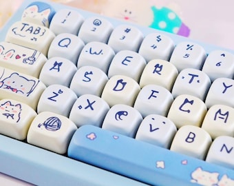 May include: A light blue keyboard with white keycaps featuring blue lettering and cute illustrations. The keycaps have various symbols, letters, and numbers. The space bar is light blue with cat and flower designs.