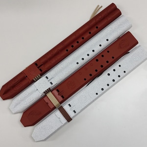Può includere: Quattro flauti in stile nativo americano nei toni del rosso e del bianco. I flauti sono fatti di legno e hanno una serie di fori lungo il corpo. Ogni flauto ha un involucro in pelle o tessuto e un design decorativo.