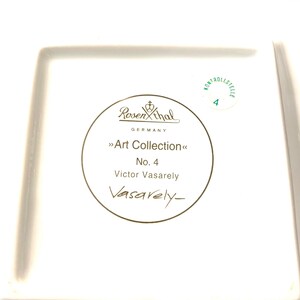 Puede incluir: Un plato cuadrado de cer&aacute;mica blanca con un borde dorado y una inscripci&oacute;n dorada que dice "Rosenthal Germany Art Collection No. 4 Victor Vasarely Vasarely-". El plato tambi&eacute;n tiene un c&iacute;rculo verde con el texto "Kontrollstelle 4" en oro.