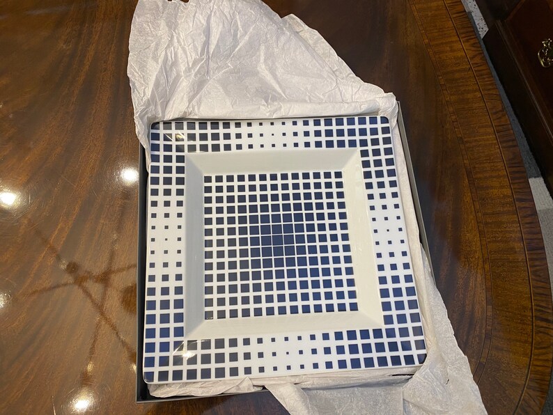 Puede incluir: Un plato cuadrado blanco para servir con un patr&oacute;n geom&eacute;trico azul. El plato est&aacute; en una caja con papel de seda.