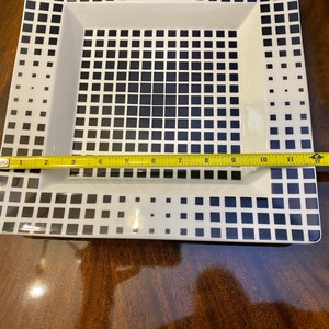 Puede incluir: Un plato cuadrado blanco para servir con un patr&oacute;n geom&eacute;trico en blanco y negro. El plato mide 35,5 cm de largo.