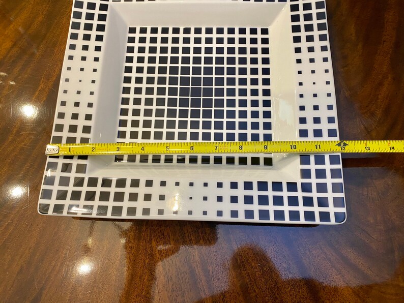 Puede incluir: Un plato cuadrado blanco para servir con un patr&oacute;n geom&eacute;trico en blanco y negro. El plato mide 35,5 cm de largo.