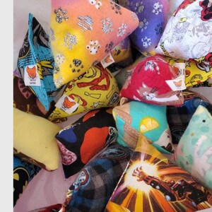 Puede incluir: Una colecci&oacute;n de coloridos juguetes triangulares para gatos. Los juguetes presentan varios patrones, incluyendo huellas de patas, personajes de c&oacute;mics y dise&ntilde;os abstractos. Cada juguete tiene una peque&ntilde;a etiqueta con un logotipo de zorro.
