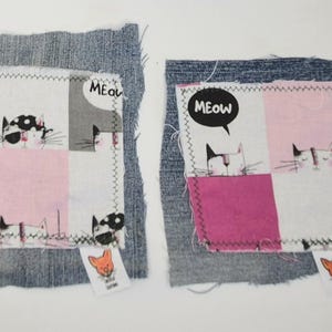 May include: Two square denim fabric patches featuring a white cotton overlay with a pink, gray, and white checkered pattern. The overlay displays cartoon cat illustrations and the text MEOW in speech bubbles, finished with a zigzag stitch.