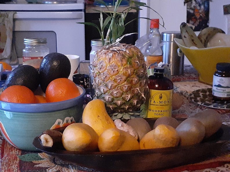 Puede incluir: Naturaleza muerta con pi&ntilde;a, naranjas, aguacates y mangos. Tambi&eacute;n hay una botella de t&oacute;nico y un frasco de Moringa. La fruta est&aacute; dispuesta en cuencos y una bandeja de madera.