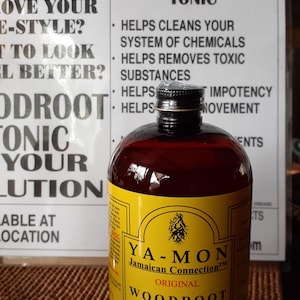 Puede incluir: Una botella de Ya-Mon Jamaican Connection Woodroot Tonic con una etiqueta amarilla y l&iacute;quido oscuro. La etiqueta incluye texto sobre los ingredientes y beneficios del producto. La botella est&aacute; frente a un letrero con texto sobre el t&oacute;nico.