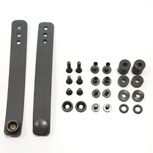 May include: Two black fabric straps with metal buckles and a set of black plastic hardware including screws, washers, and grommets.