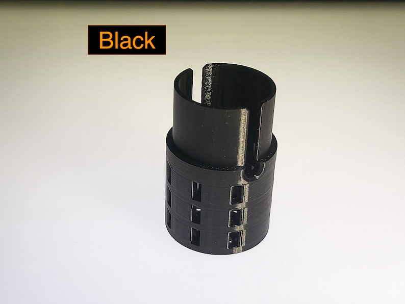 May include: Black plastic 3D printed object with a cylindrical shape and a series of holes around the middle.