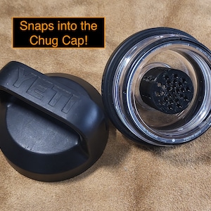 May include: Two black Yeti brand lids for a water bottle. One lid has a handle and the other lid has a clear plastic insert with a black mesh filter. The text "Snaps into the Chug Cap!" is written in orange above the lids.
