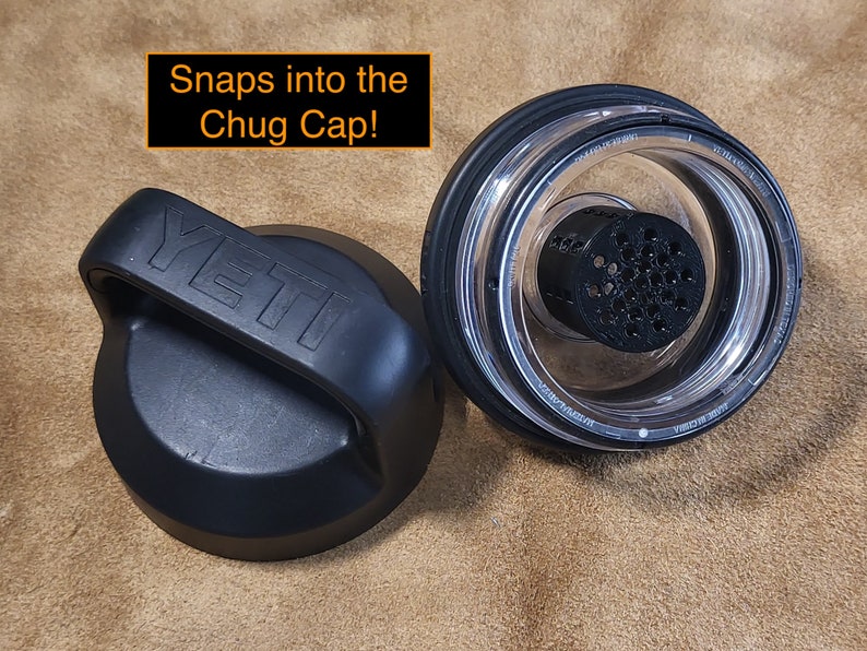 May include: Two black Yeti brand lids for a water bottle. One lid has a handle and the other lid has a clear plastic insert with a black mesh filter. The text "Snaps into the Chug Cap!" is written in orange above the lids.