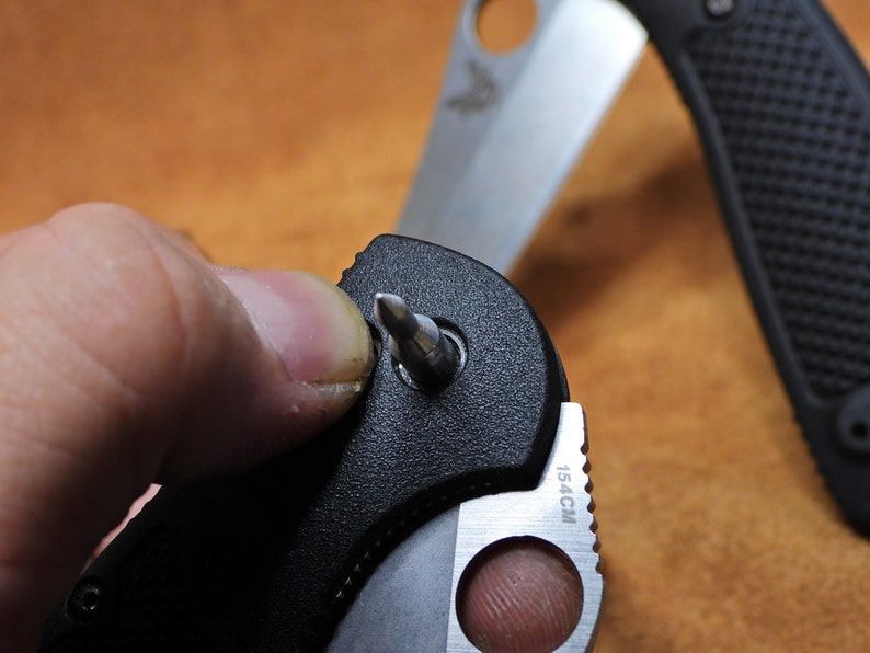 May include: A black folding knife with a silver blade and a small screwdriver tool. The knife is partially open and the screwdriver is extended. The knife has a black handle with a textured grip and the blade has a 15.4CM marking.