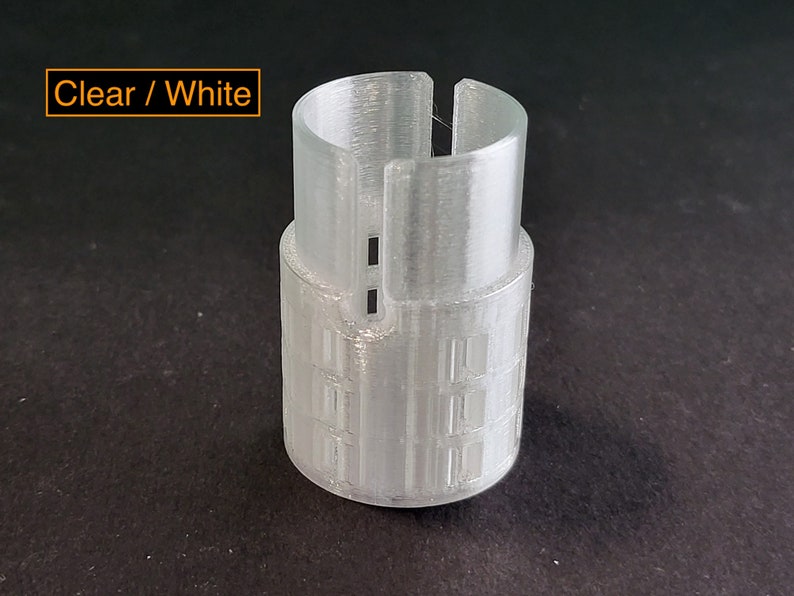 May include: A clear white plastic tube with a textured surface and a small opening at the top. The tube has a series of horizontal lines around the middle.