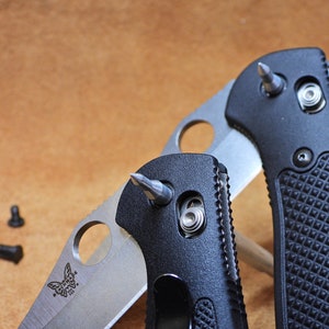 May include: Two black pocket knives with silver blades and a silver tip on the end of the handle. The knives have a textured black handle and a silver butterfly logo on the blade.