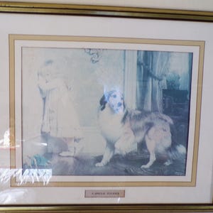 May include: Framed print featuring a child and a dog in a domestic setting. The dog is a large breed with a mix of brown, white, and black fur. The child is wearing a white dress. The print is in a gold frame.