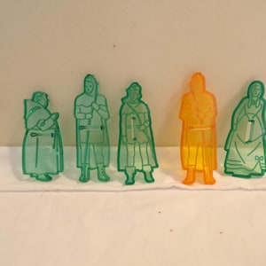 May include: Set of six green and orange plastic cookie cutters shaped like people in medieval clothing.