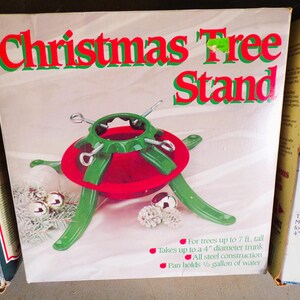 May include: A green metal Christmas tree stand with a red base. The stand is designed to hold a tree up to 7 feet tall and a trunk up to 4 inches in diameter. The stand is made of all steel construction and holds 1/2 gallon of water.
