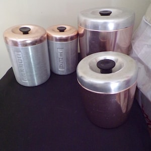 May include: Set of four vintage copper and silver canisters with lids. The canisters are labeled "Coffee", "Tea", and two unlabeled canisters.