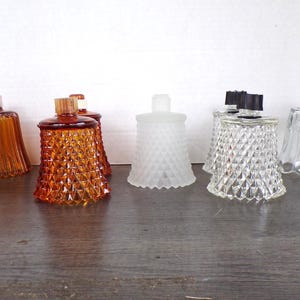 May include: A collection of eight glass candle cups in various styles and colours. The set includes amber-coloured cups with vertical ribs or diamond patterns, a frosted white diamond-patterned cup, and clear glass cups with diamond or scalloped designs.